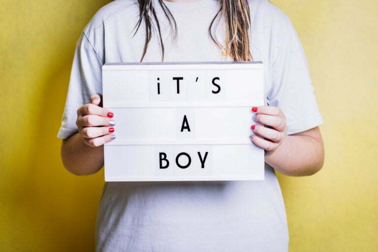 Girl holding a light box with the phrase "it's a boy".