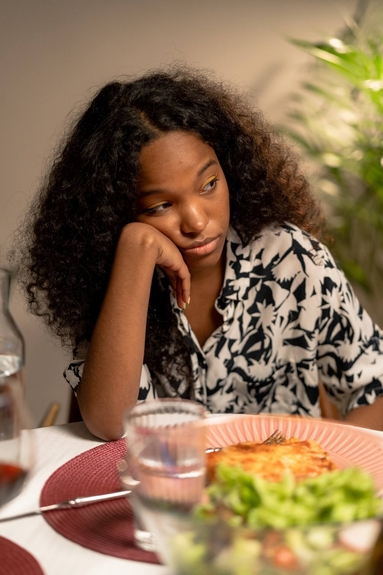 a woman with curly hair sitting at a table with a plate of food